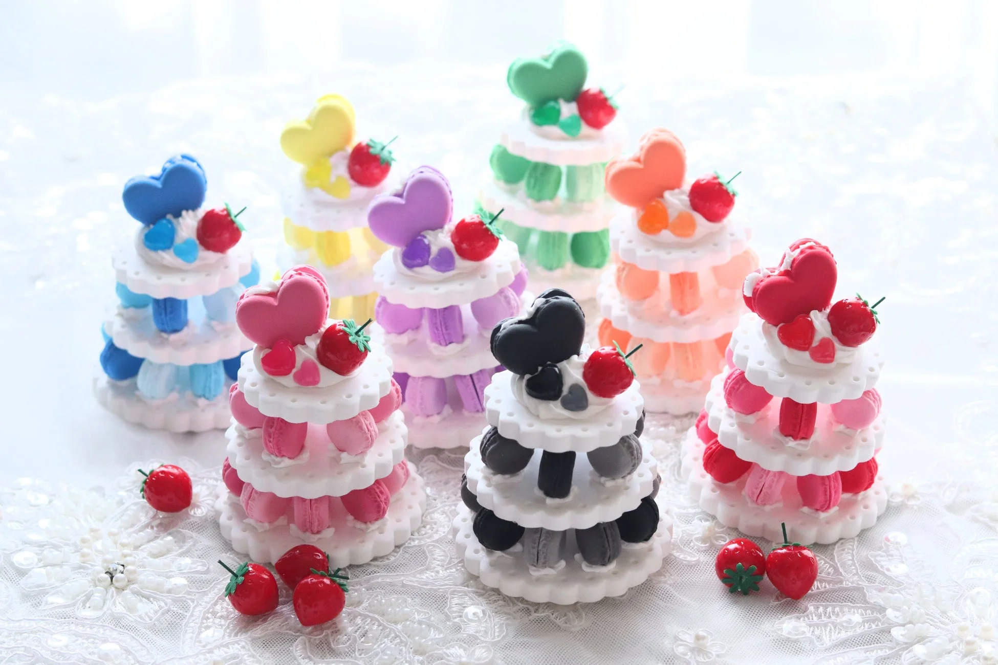 白く繊細なレースの上に、様々な色合いのミニチュアのマカロンタワーが並べられています