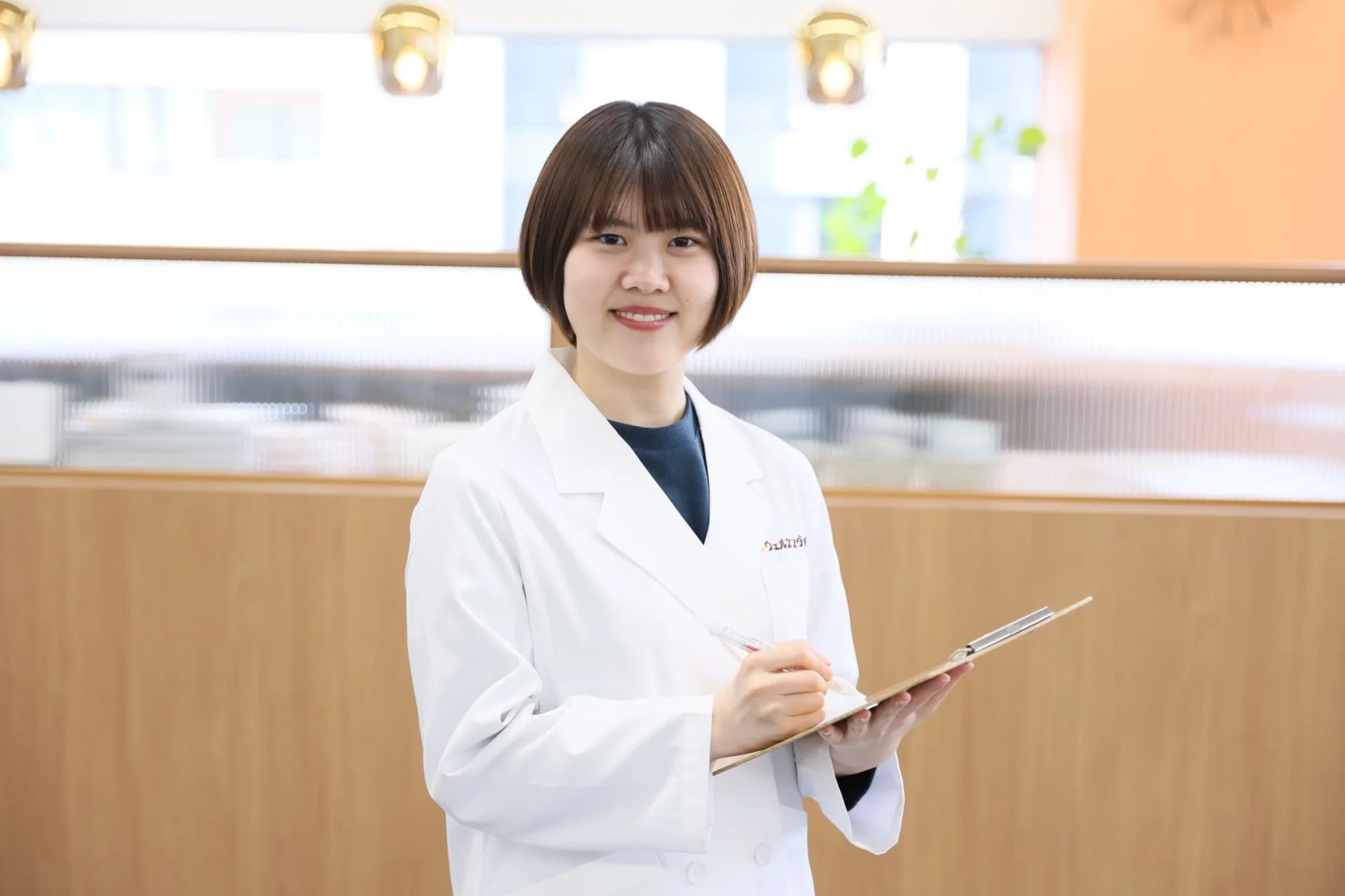 白衣を着て笑顔でクリップボードに書き込む女性