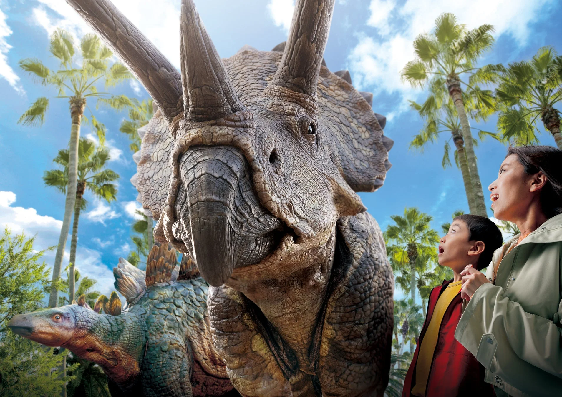 巨大なトリケラトプスの模型を見上げる親子