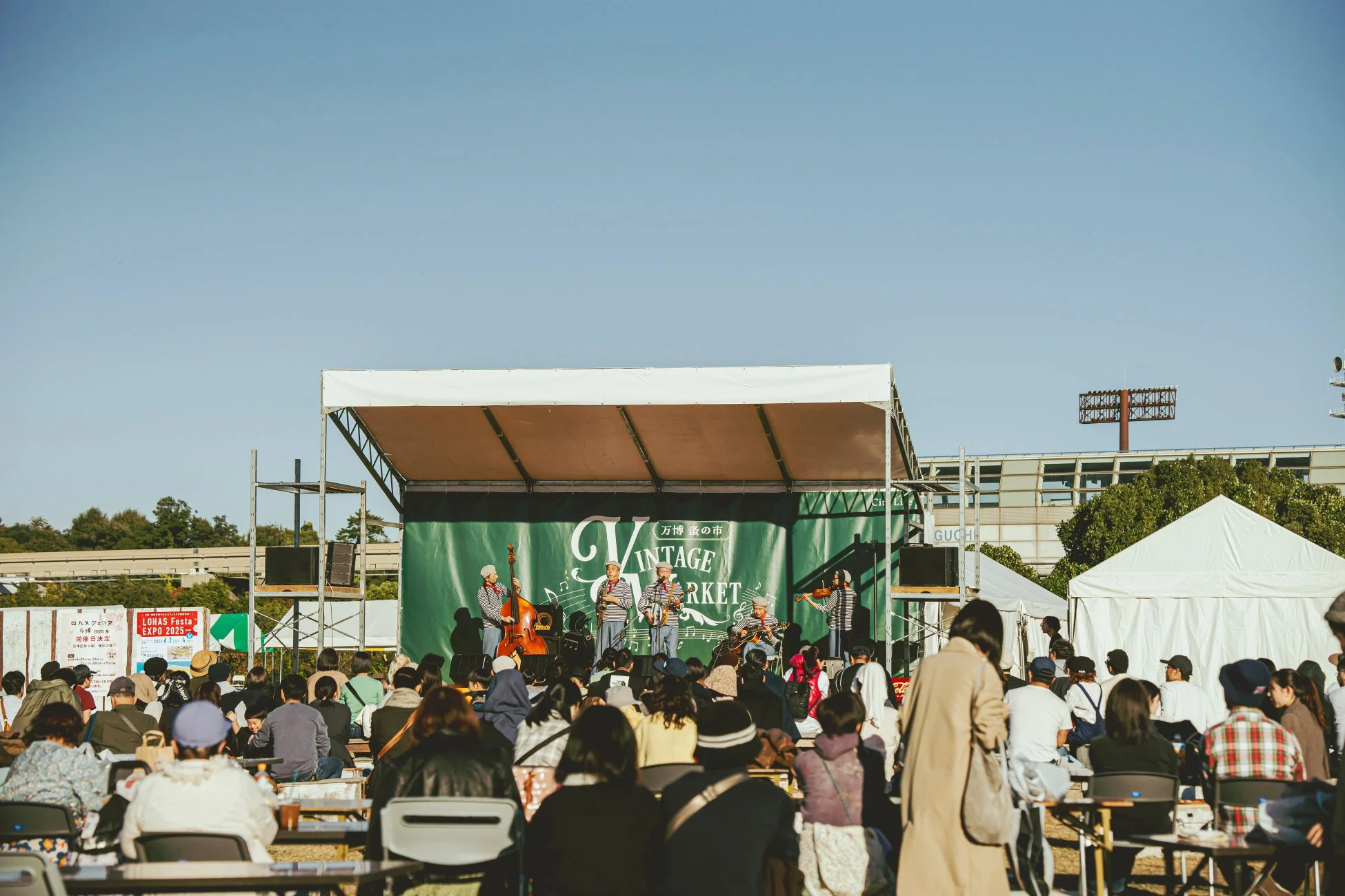 野外のステージで演奏するバンドと多くの観客