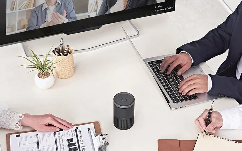 会議室でスピーカーフォンを使ってWeb会議をするビジネスパーソン