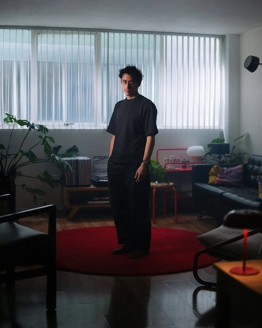 黒い服を着た若い男性がモダンなリビングルームに立っている