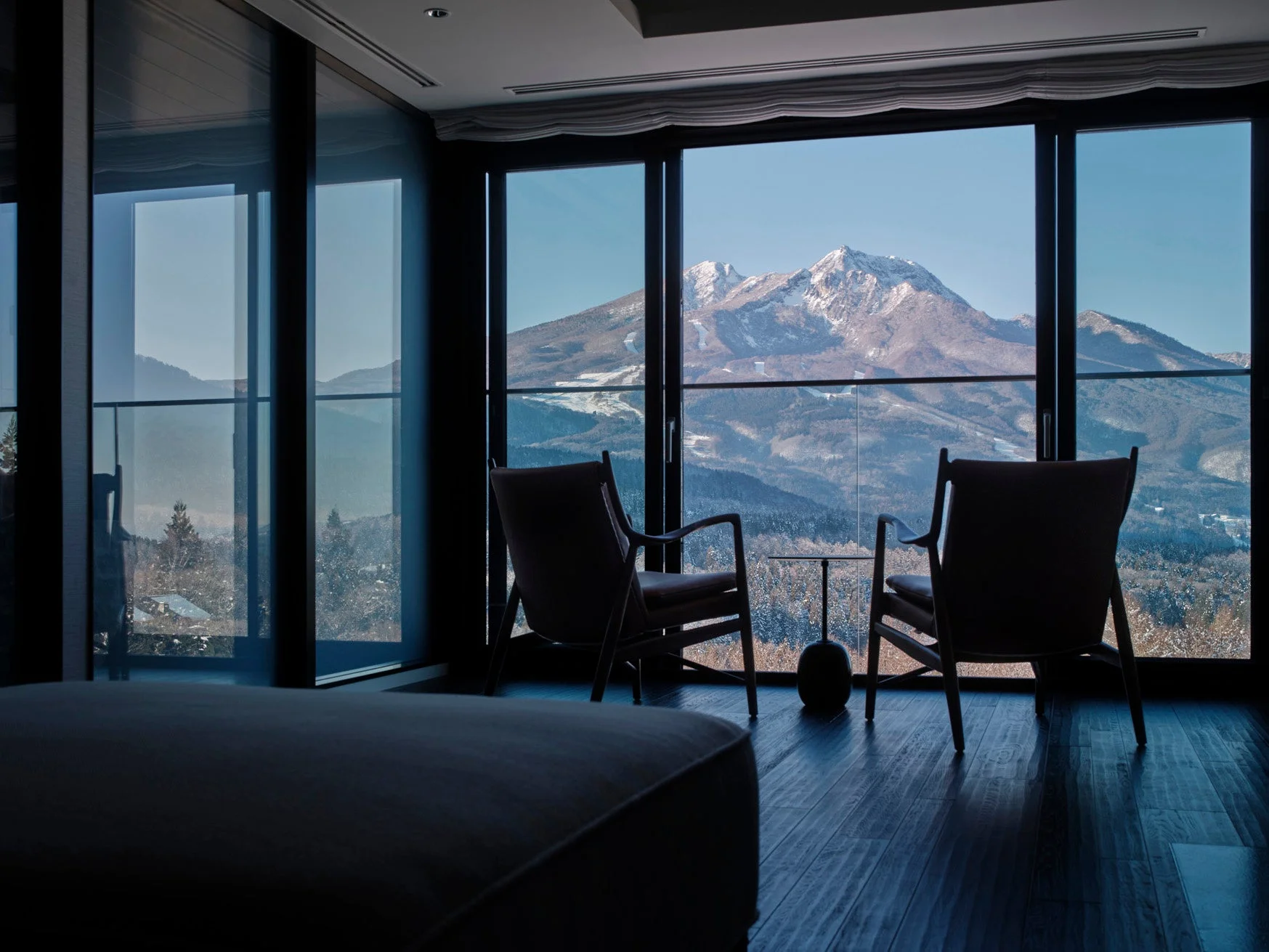 窓から雪をまとった雄大な山々を望むモダンな室内