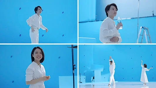 白い衣装を身につけた複数の人物が、ブルーバックのスタジオで撮影に臨んでいる