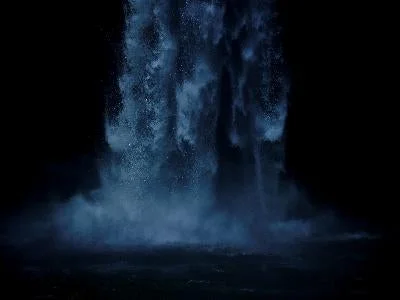 暗闇の中で大量の水が勢いよく流れ落ちる滝