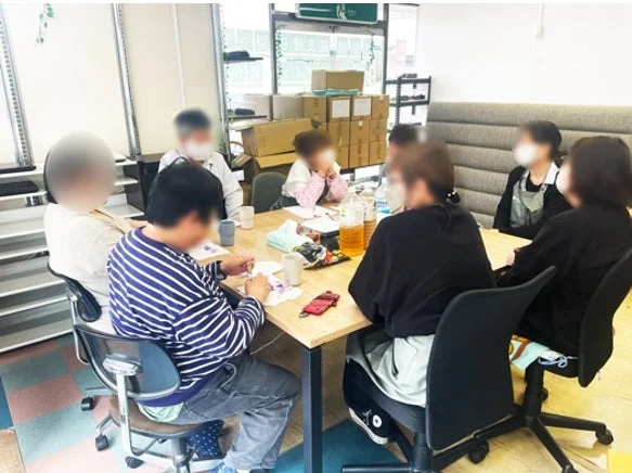 人々がテーブルを囲んで話し合いや作業をしている様子