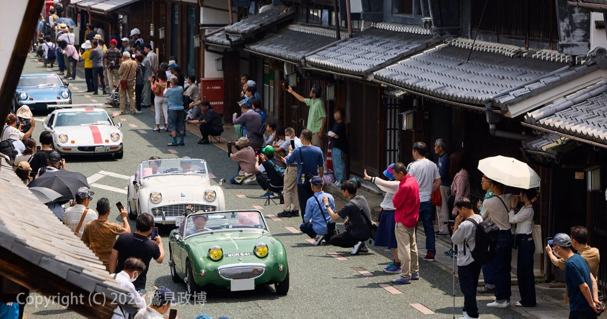 クラシックカーのパレードを見物する人々