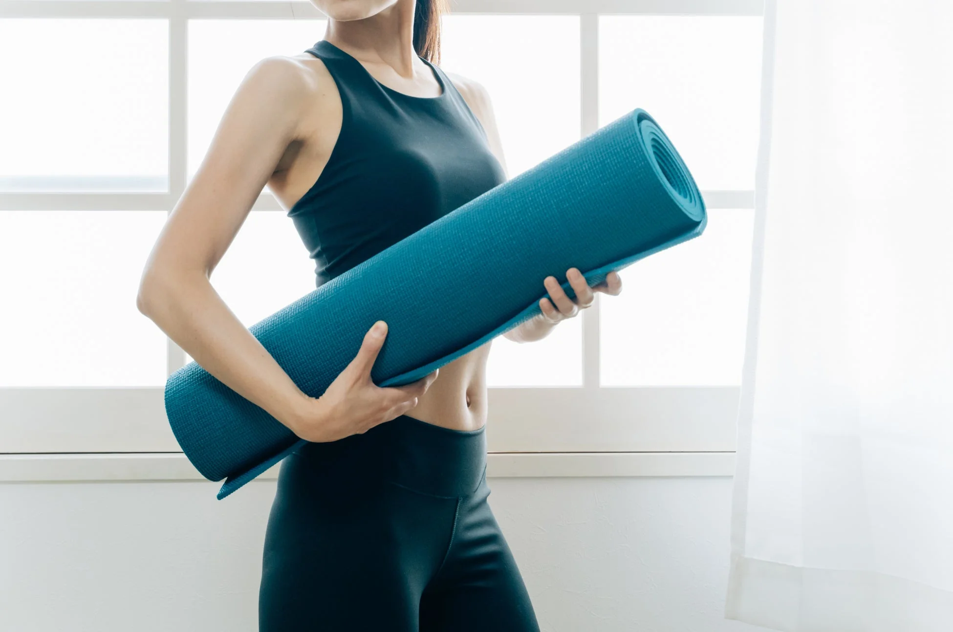 ヨガマットを抱える女性