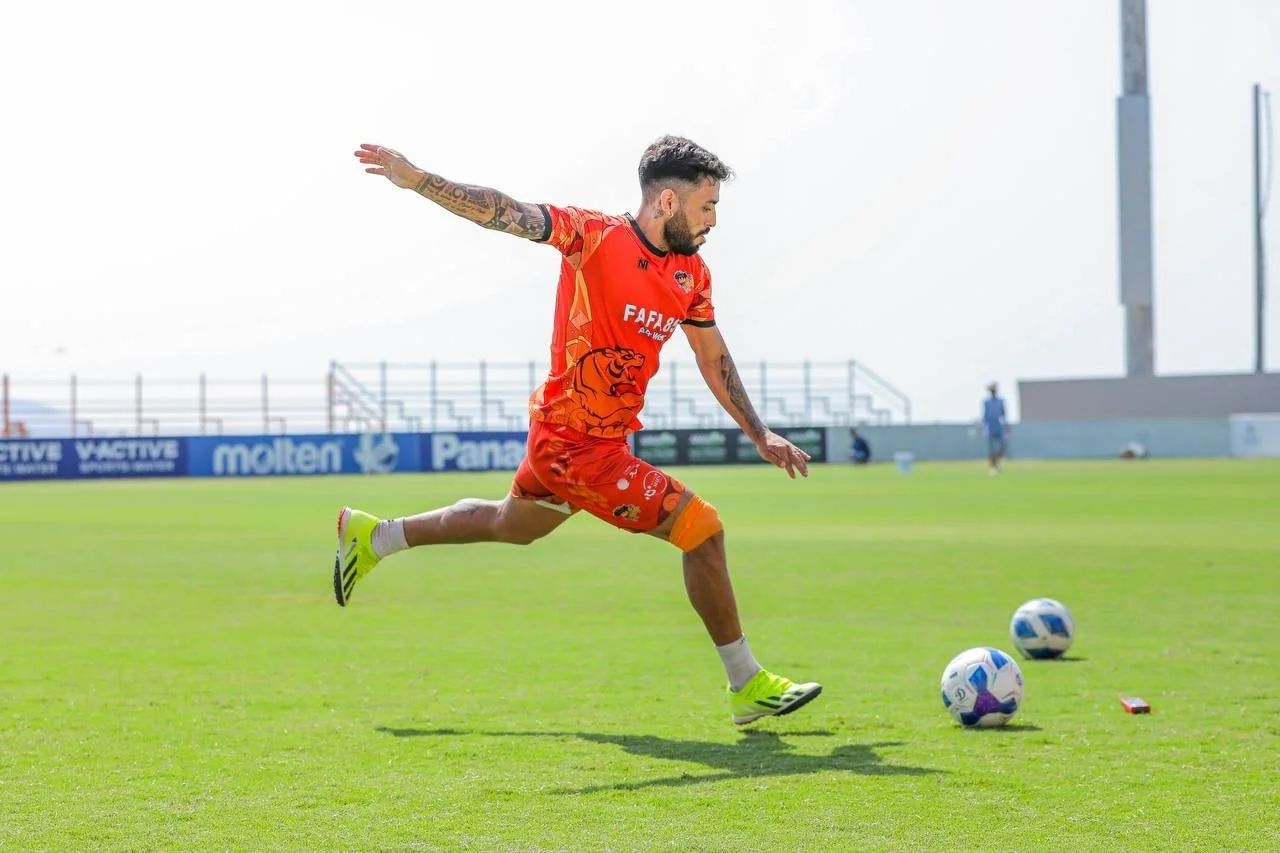 オレンジ色のユニフォームを着たサッカー選手がジャンプしている