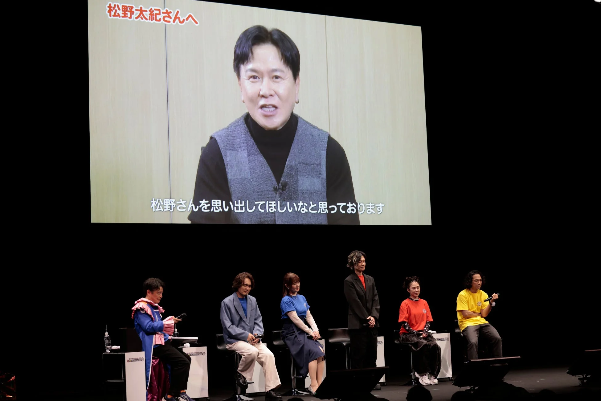 スクリーンに映し出された男性の映像と「松野太紀さんへ」のメッセージ