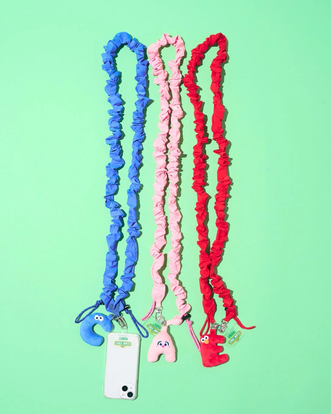 青、ピンク、赤のカラフルなシュシュ型電話ストラップが3本並んでいます