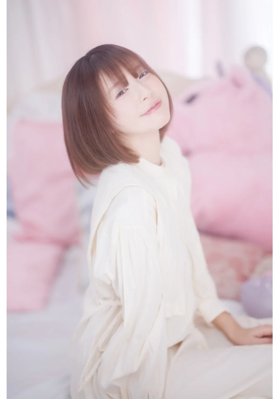 白い服を着たショートヘアの女性が優しく微笑んでいます