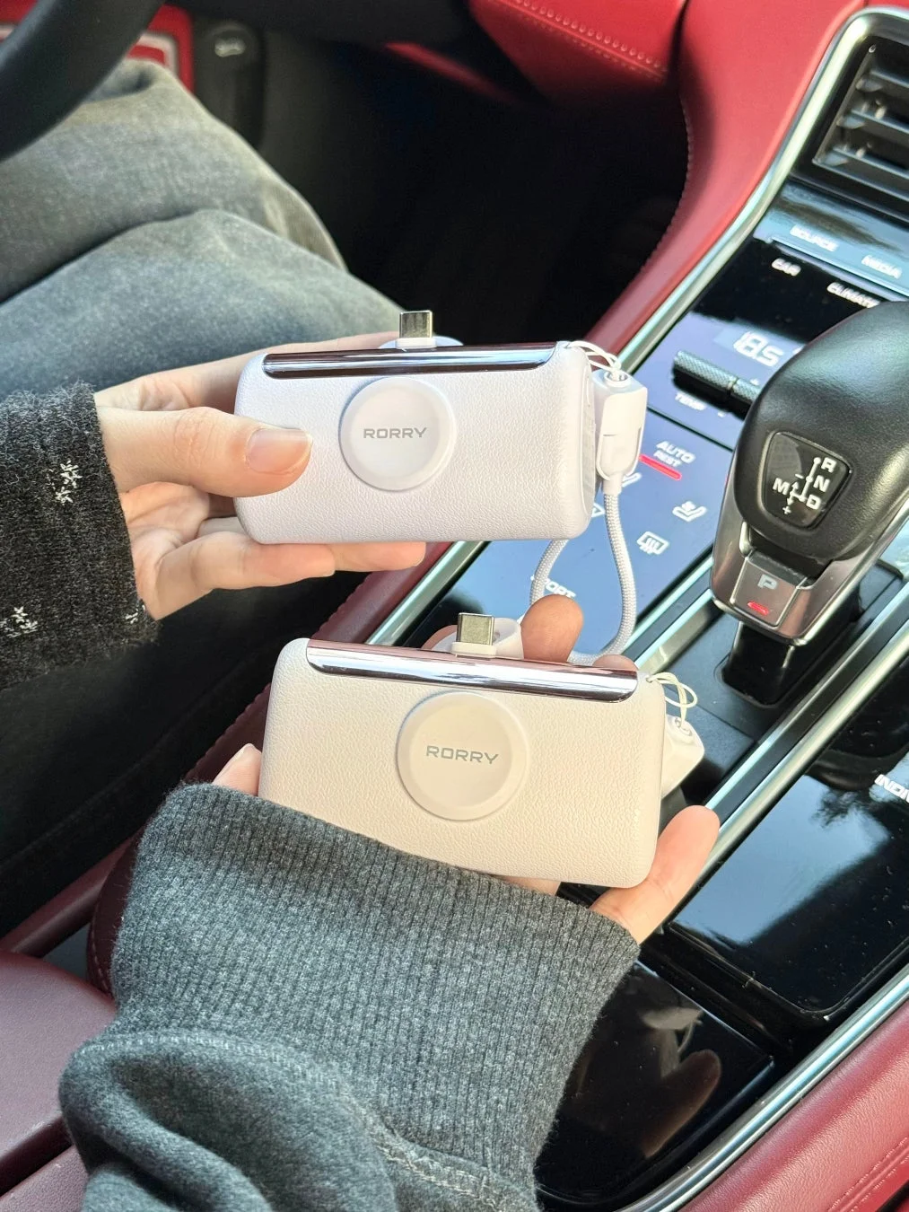 車内でモバイルバッテリーを両手が持っている様子
