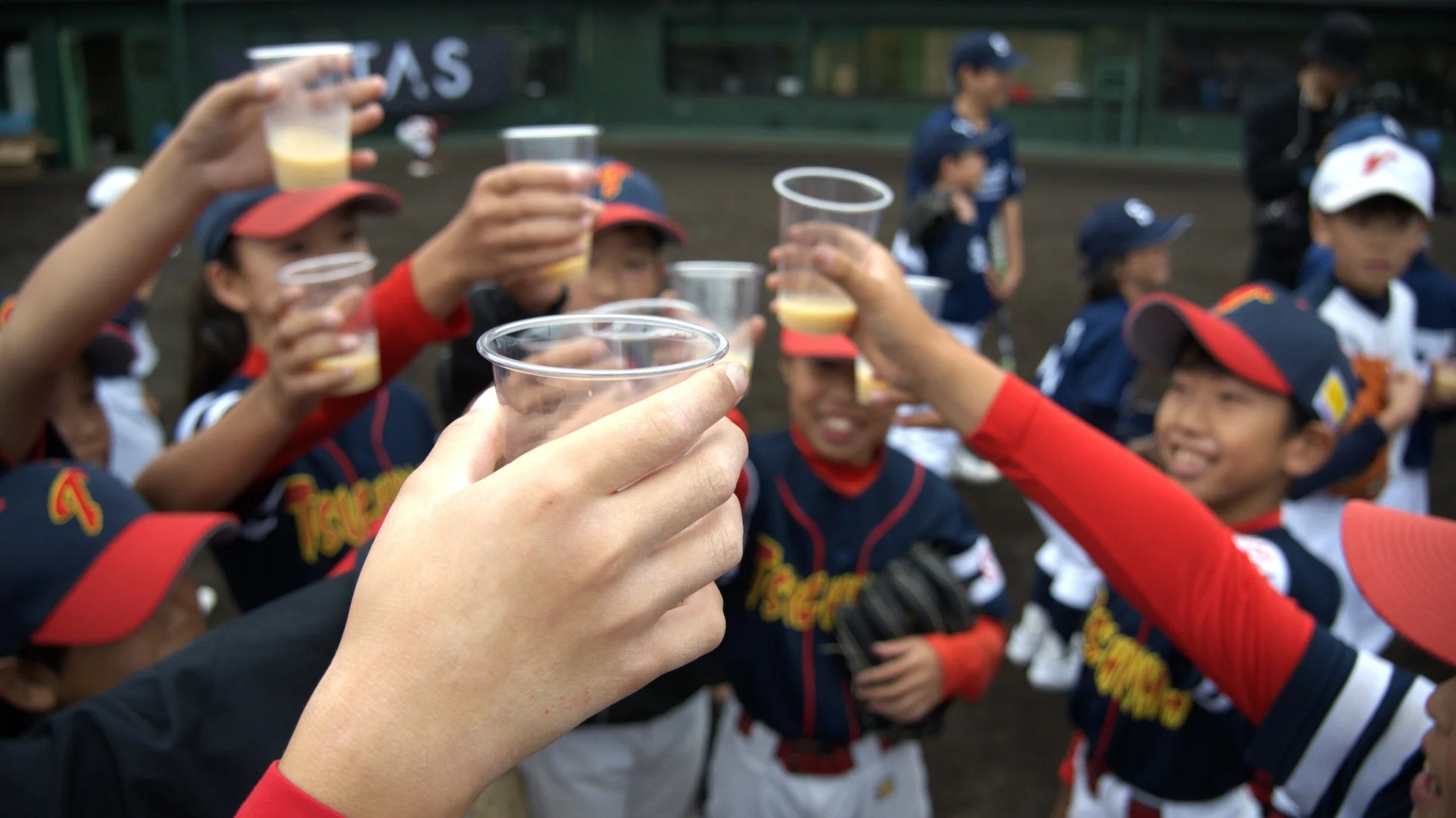 野球のユニフォームを着た子供たちが乾杯している様子