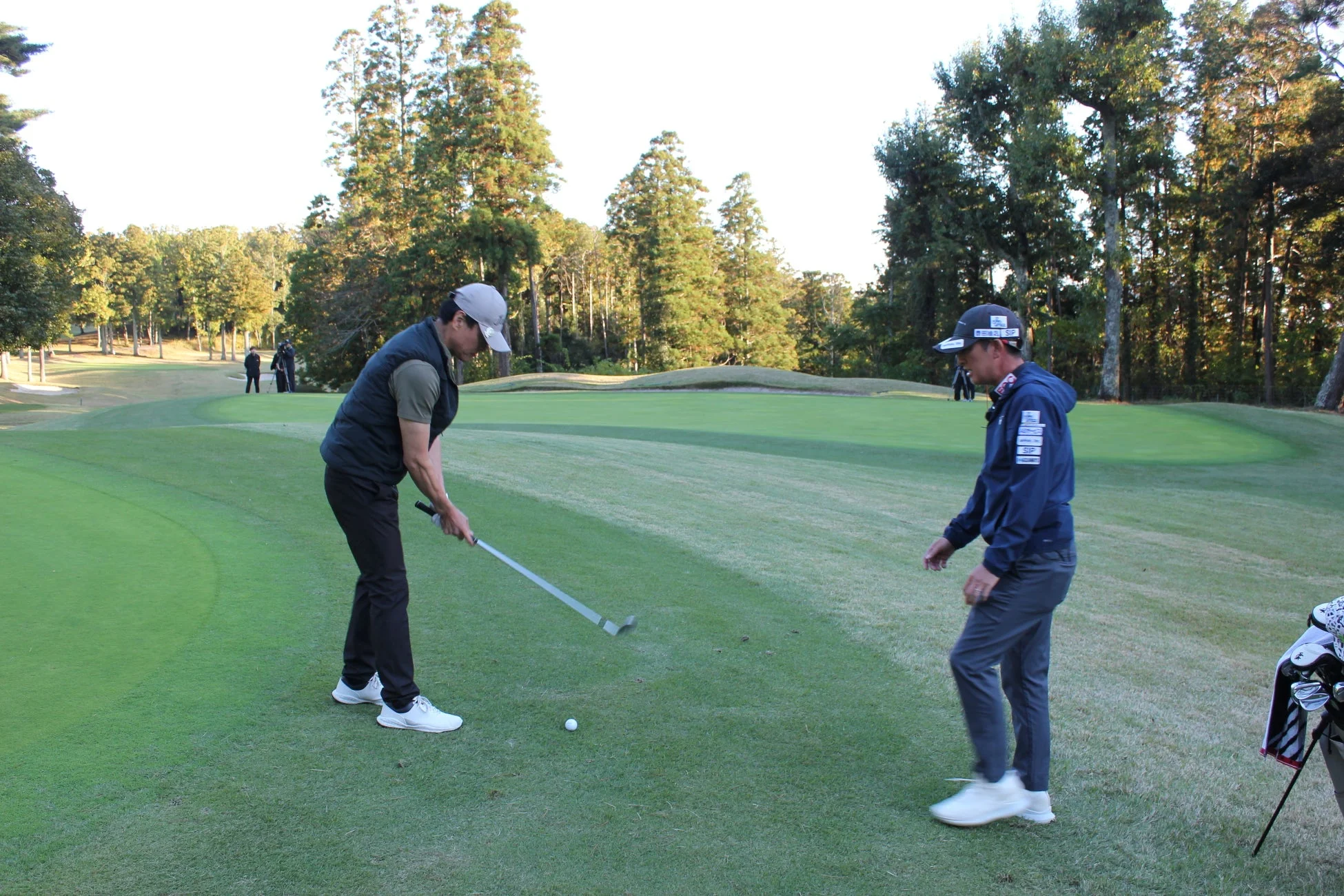 ゴルフコースで、一人の男性がゴルフボールを打とうとしており