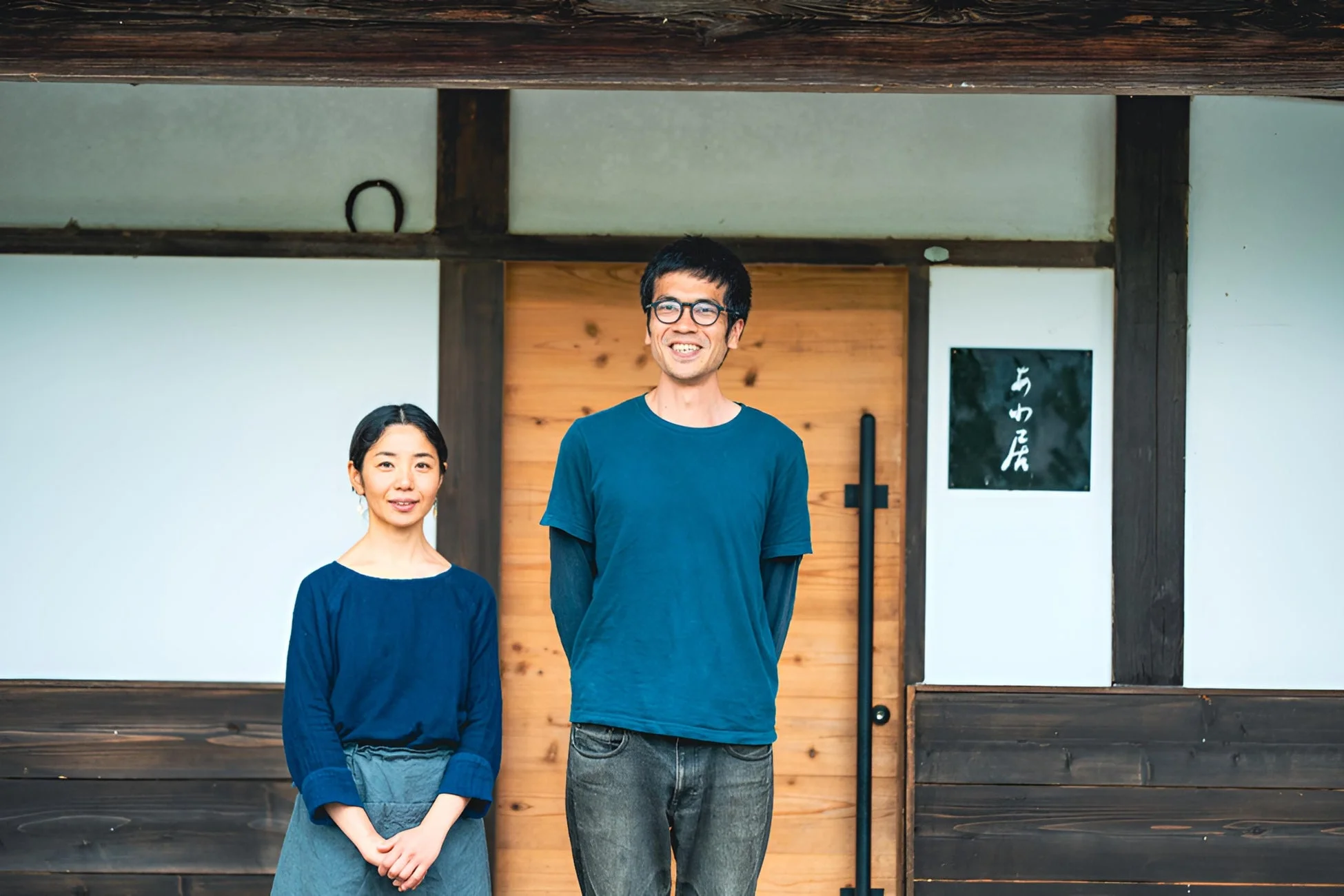 伝統的な家屋の前に立つ笑顔の男女