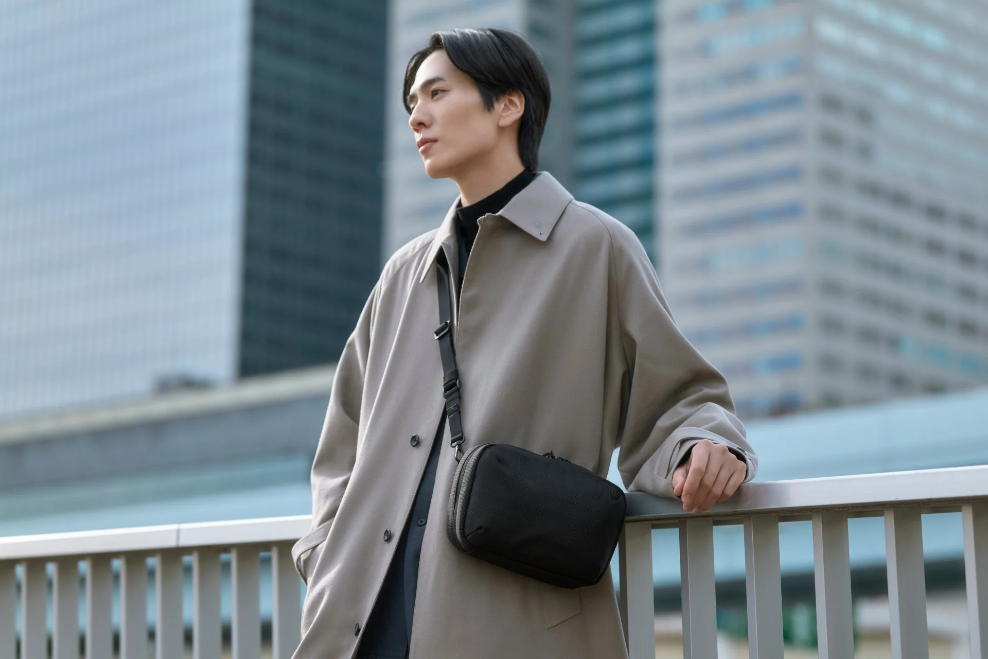 都会のビル群を背景にショルダーバッグを身につけた男性