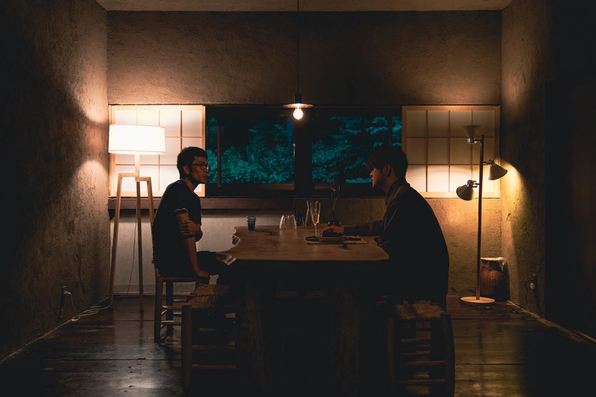 夜の室内で男性二人が会話する様子