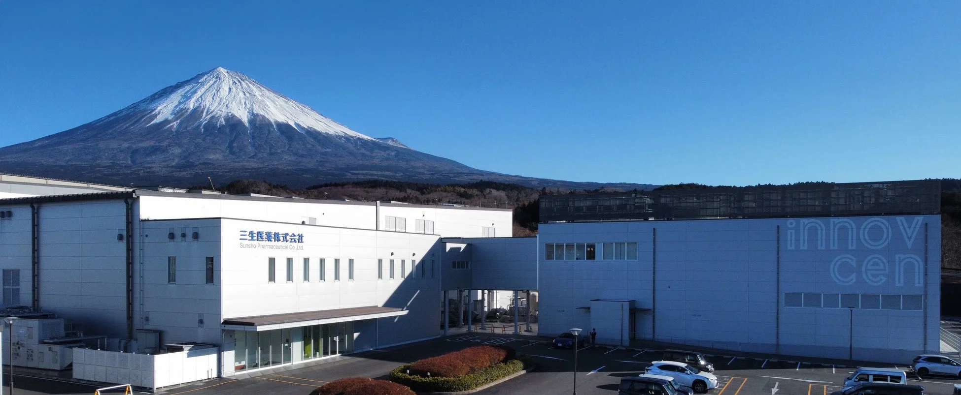 雪をかぶった富士山を背景に広がる三生医薬株式会社の建物
