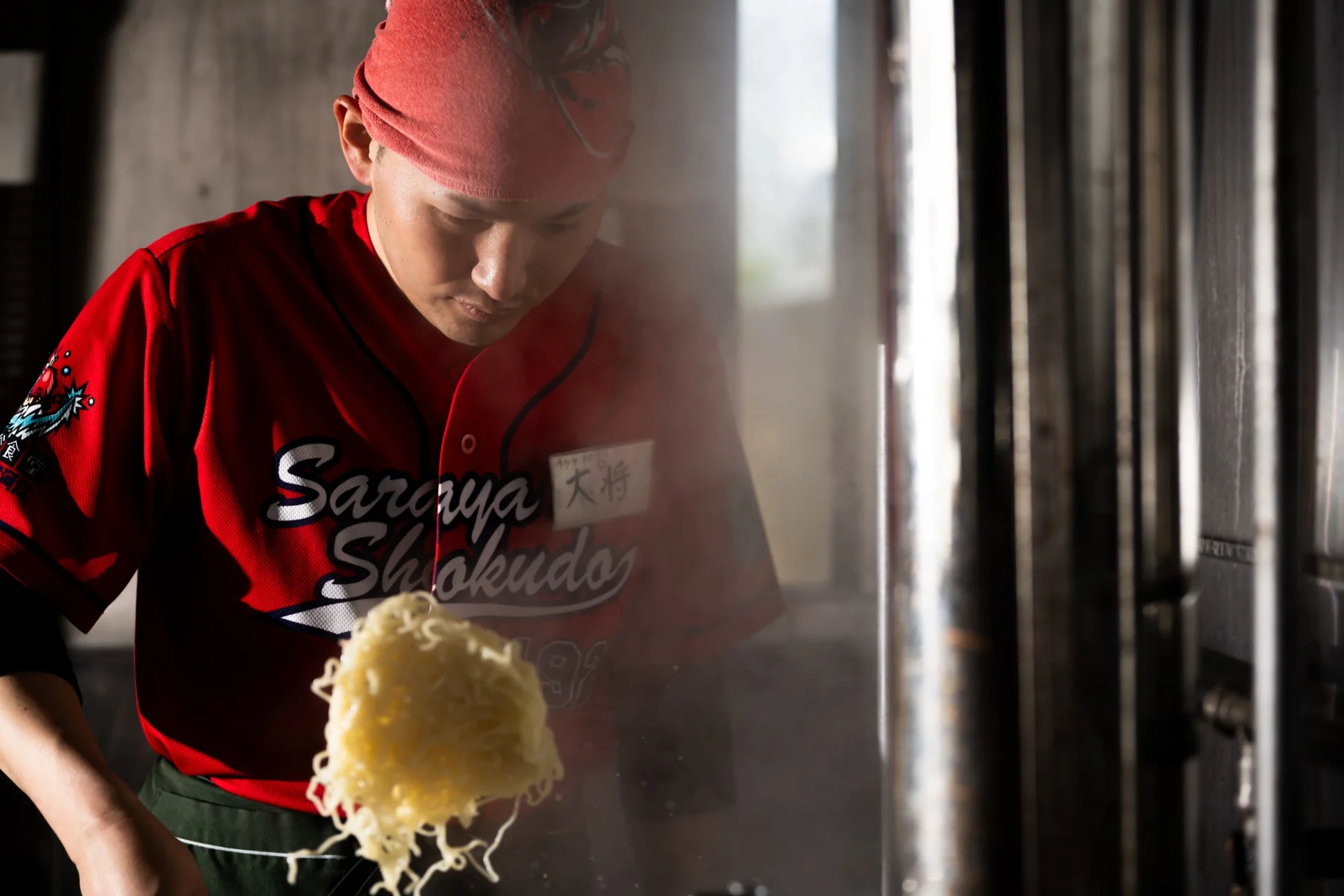 厨房で麺を調理する料理人