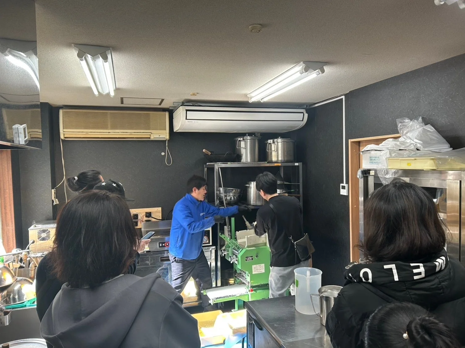 厨房で食品加工機を囲む人々