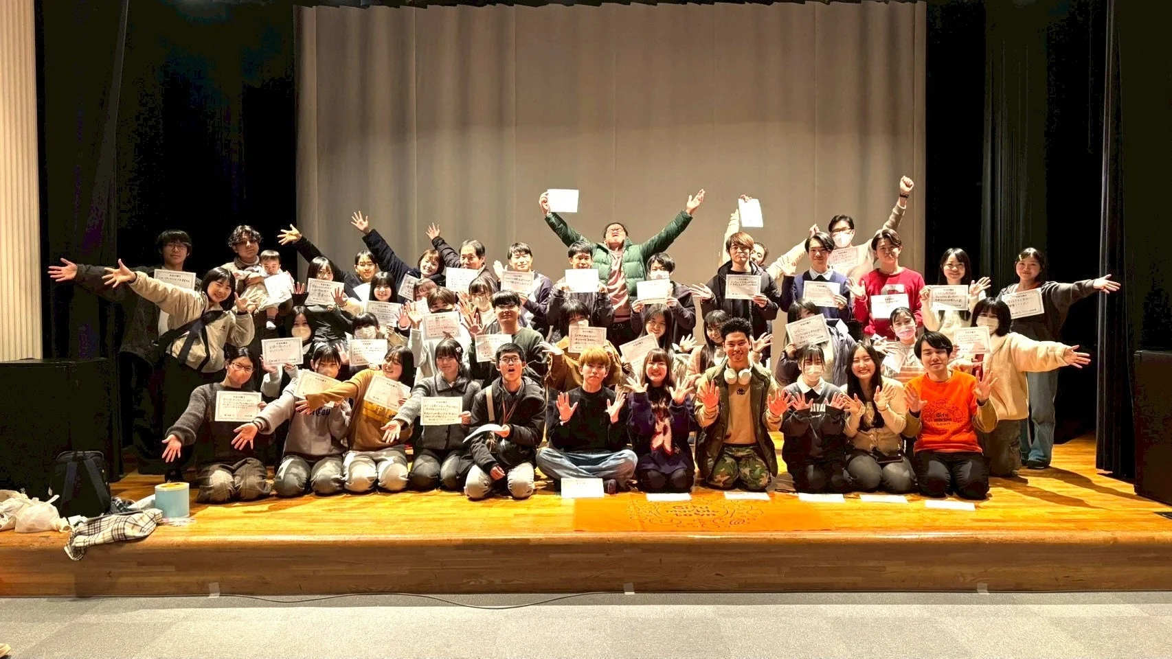 画像内の多くの人々が証明書のような書類を手に持っており