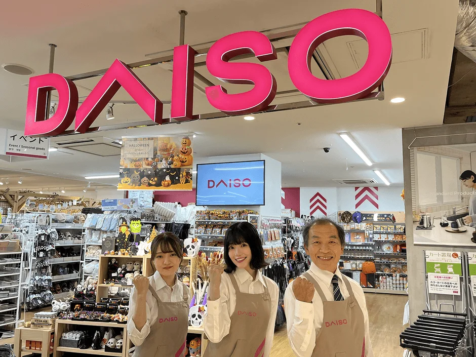 ダイソーの店舗内で店員が笑顔で拳を上げている