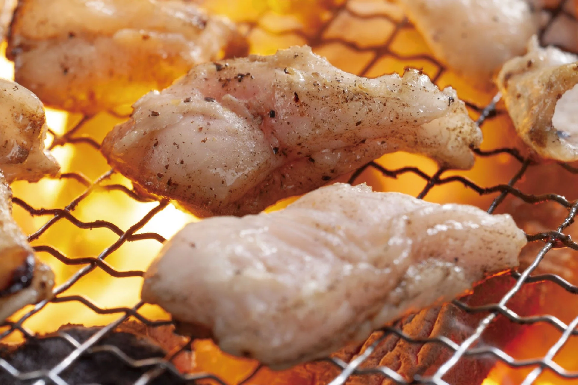 網の上で焼かれている、胡椒が振られた肉