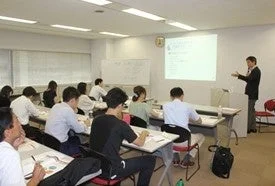 教室で男性講師が受講者たちに講義を行っている様子