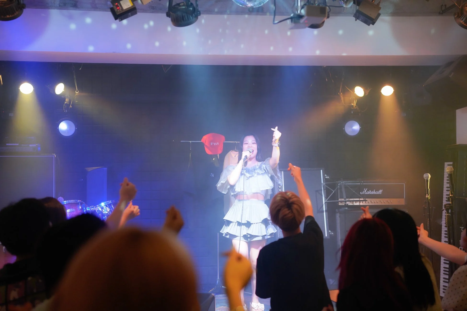 ライトアップされたステージで、女性歌手がマイクを手に歌唱