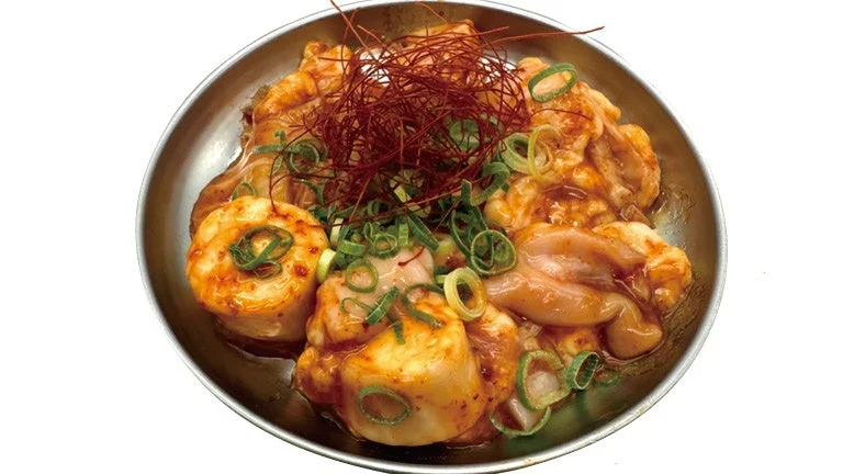 鉄製の皿に盛られた、赤みがかったタレで和えられたホルモン料理