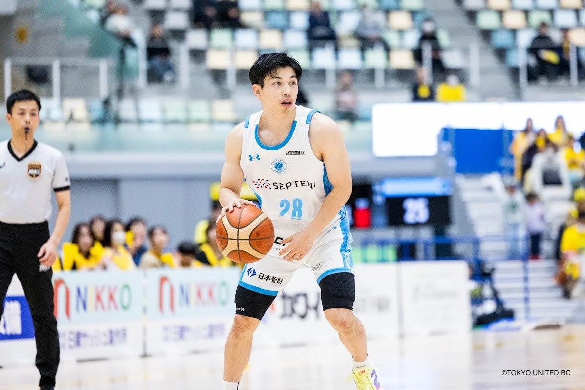 バスケットボールの試合中、28番のユニフォームを着た男性選手がボールを保持している姿を捉えた一枚。審判や観客も背景に見え、緊迫したゲームの雰囲気が伝わります。