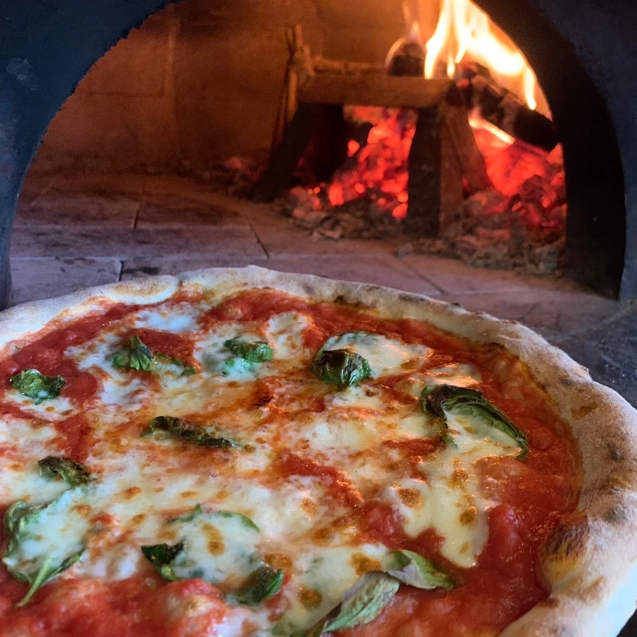 薪窯の前に置かれた、焼きたてのマルゲリータピザ