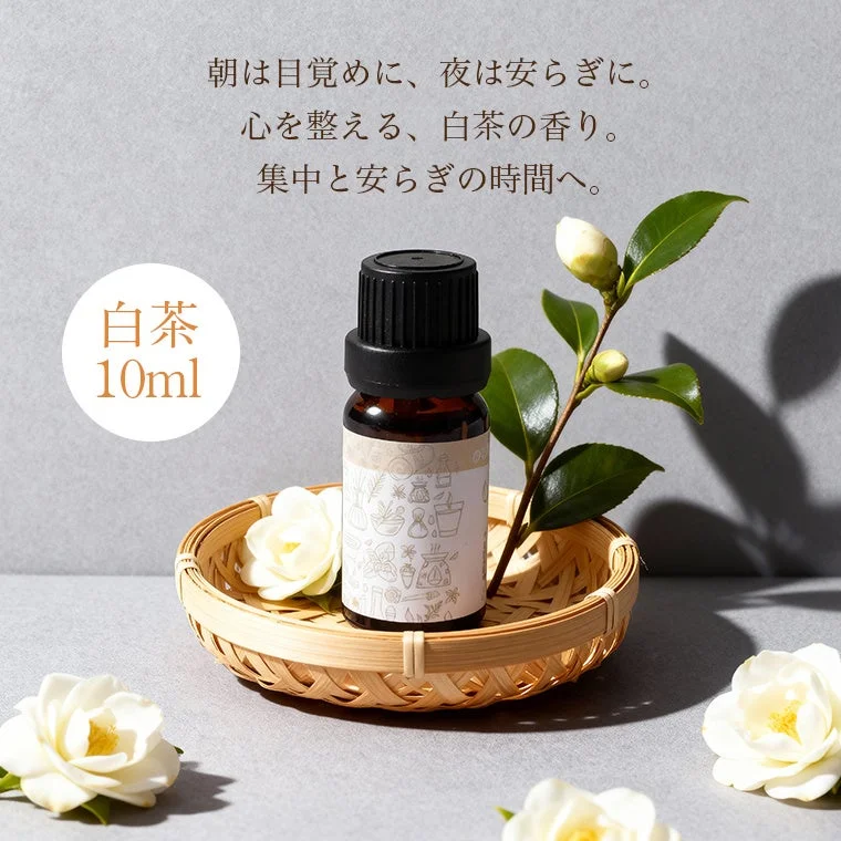 白茶のアロマオイルボトルとカメリアの花