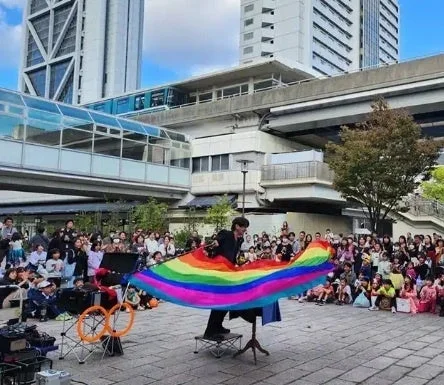 虹色の大きな布で観客を楽しませるストリートパフォーマー
