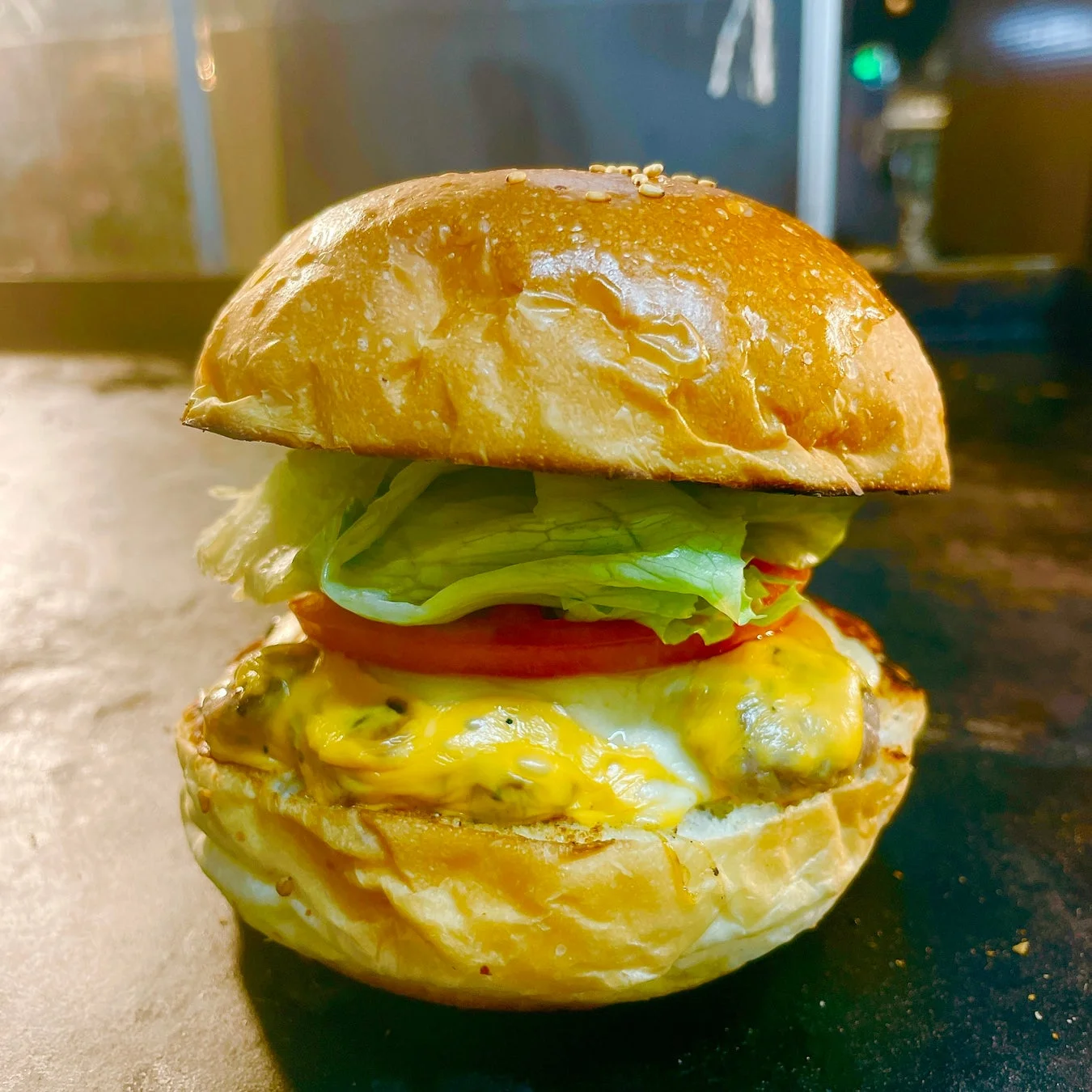 焼きたてのバンズに、とろけるチーズがたっぷりかかったパティ、新鮮なレタスとトマトが挟まれたハンバーガー