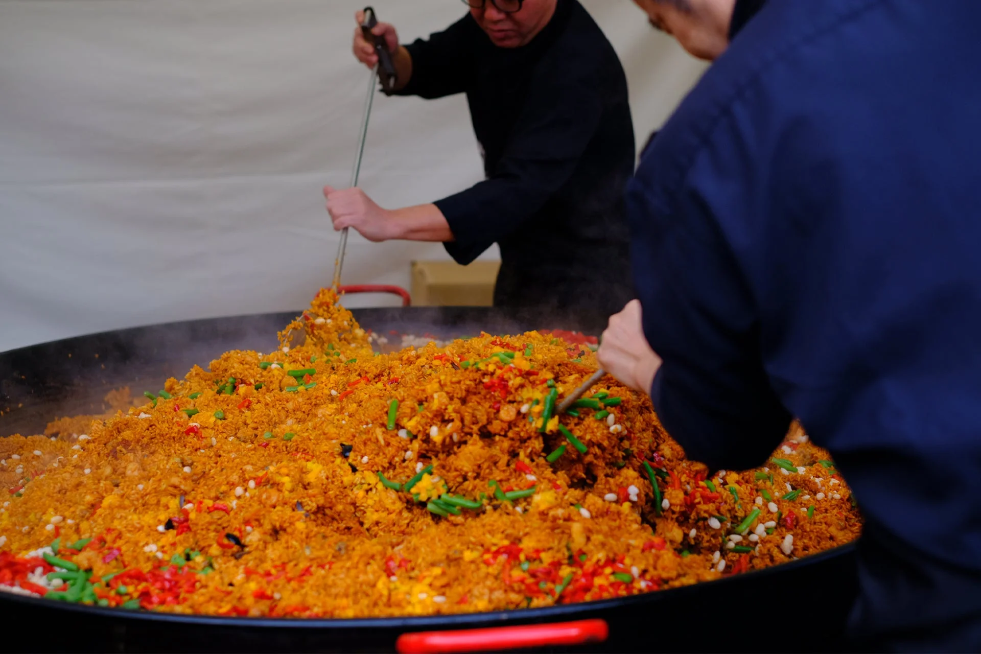 シェフが大きな鍋でパエリアを調理している様子