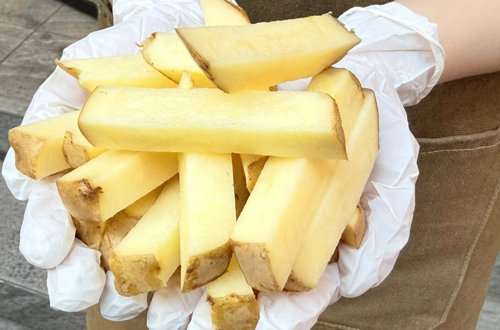 白い手袋をはめた手が、皮付きの厚切りフライドポテトを両手いっぱいに抱えている