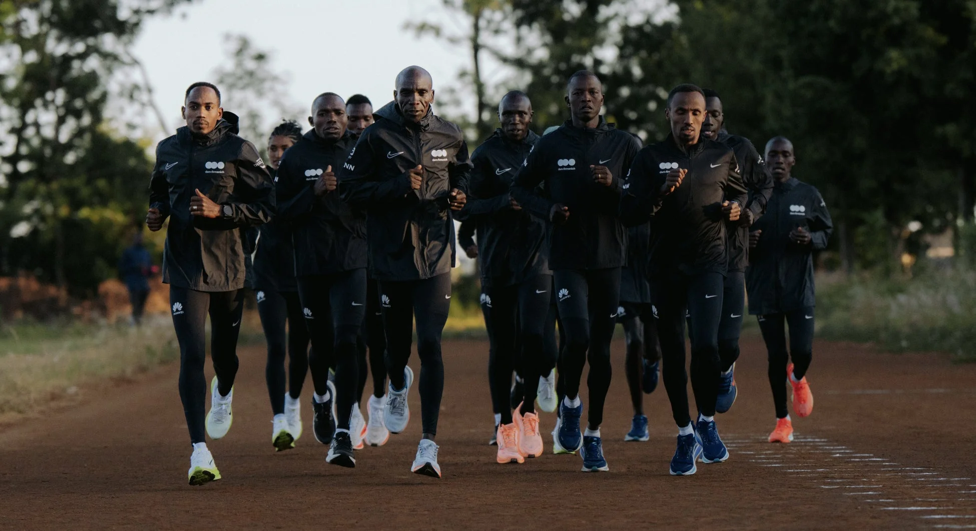 黒いウェアを着たランナーたちが土の道をグループで走っている様子