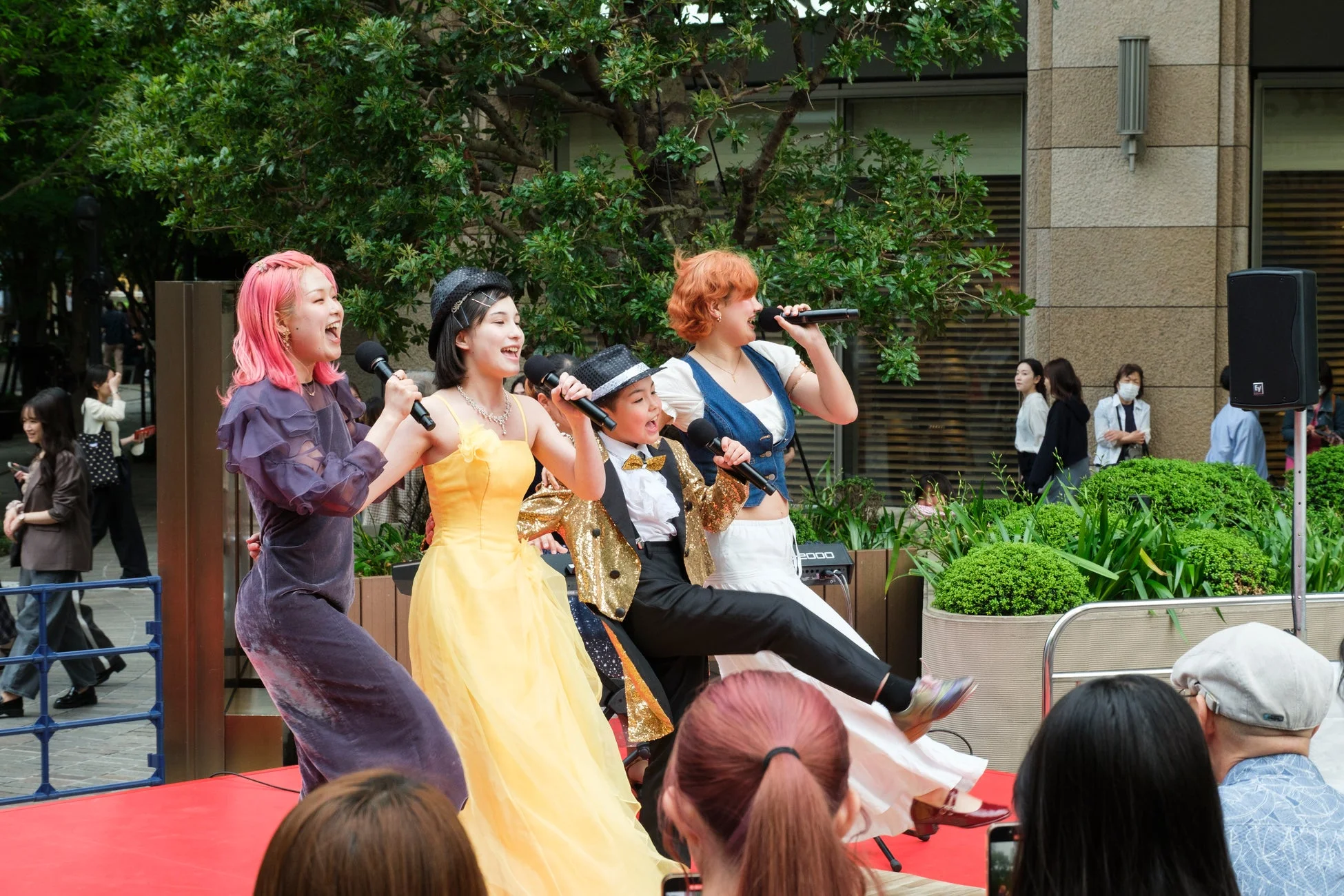 屋外ステージで歌唱パフォーマンスをする人々