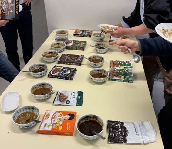 様々な種類のレトルトカレーが試食会で並べられている様子