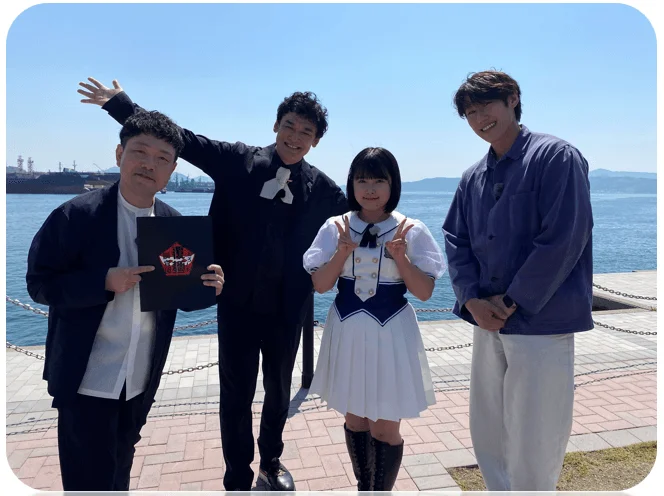 海辺で笑顔でポーズをとる「ひろしま覆麺調査団」のメンバー