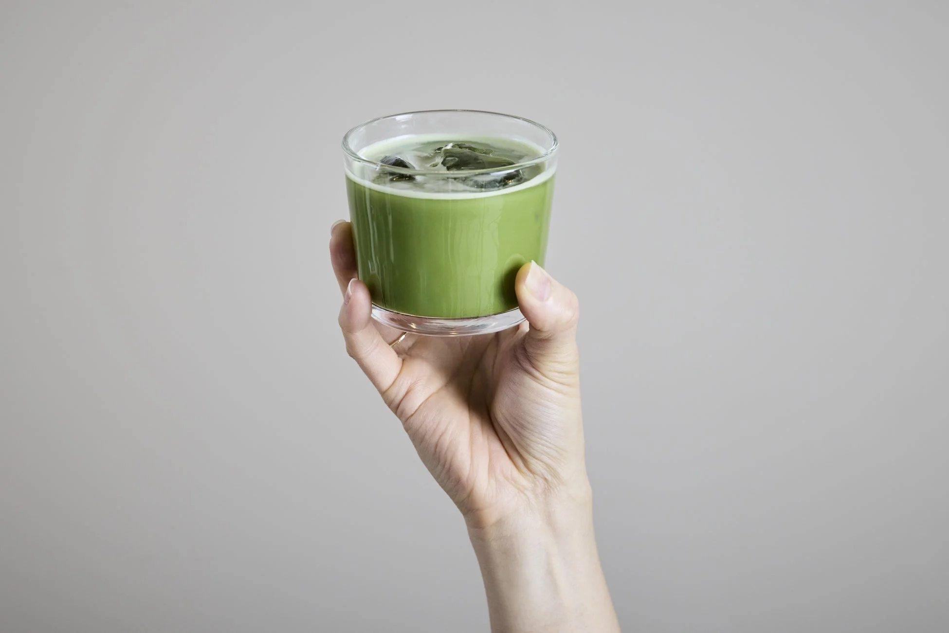 氷が入った抹茶ラテのグラスを持つ手