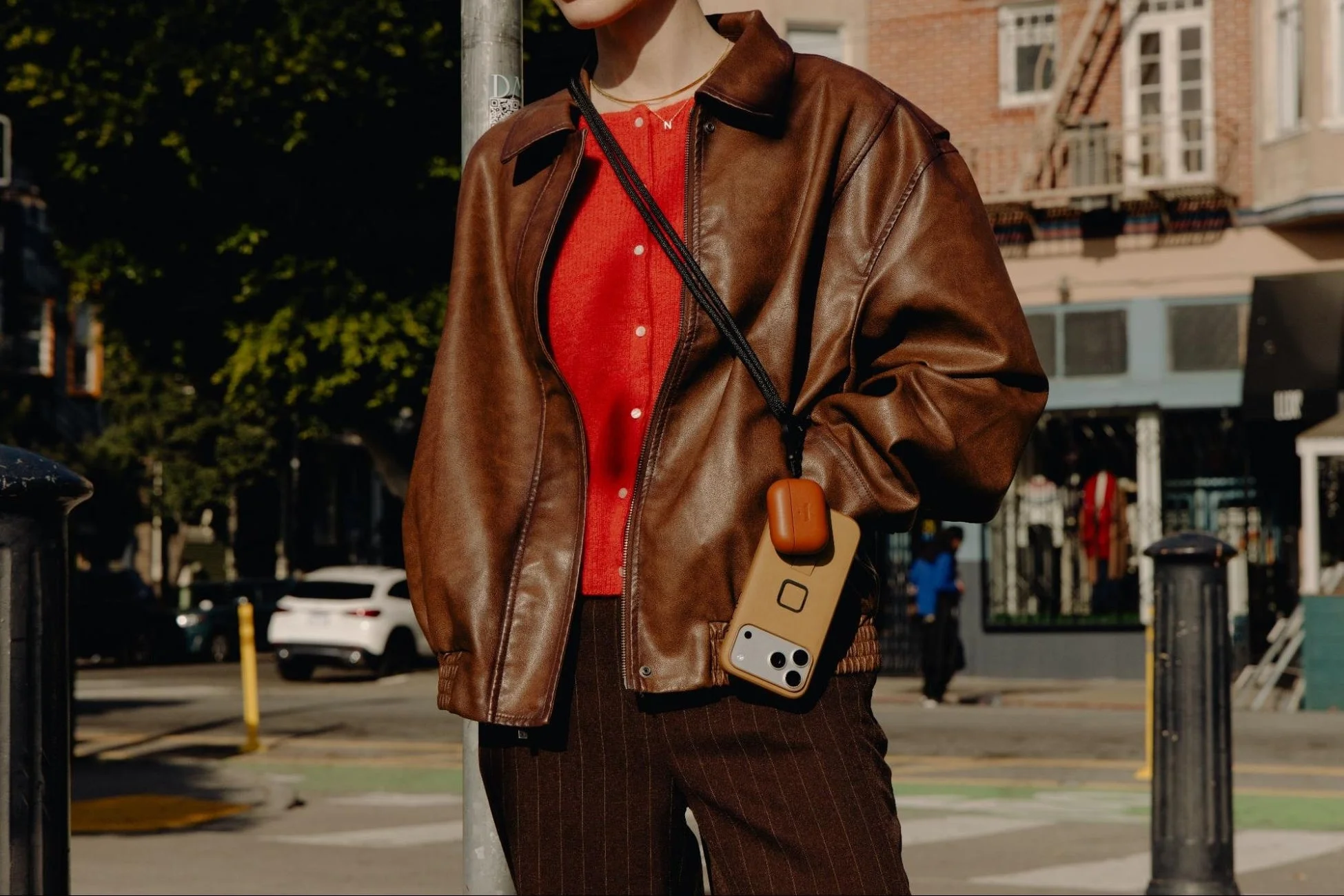 スマホとAirPodsケースをストラップで身につけた人物