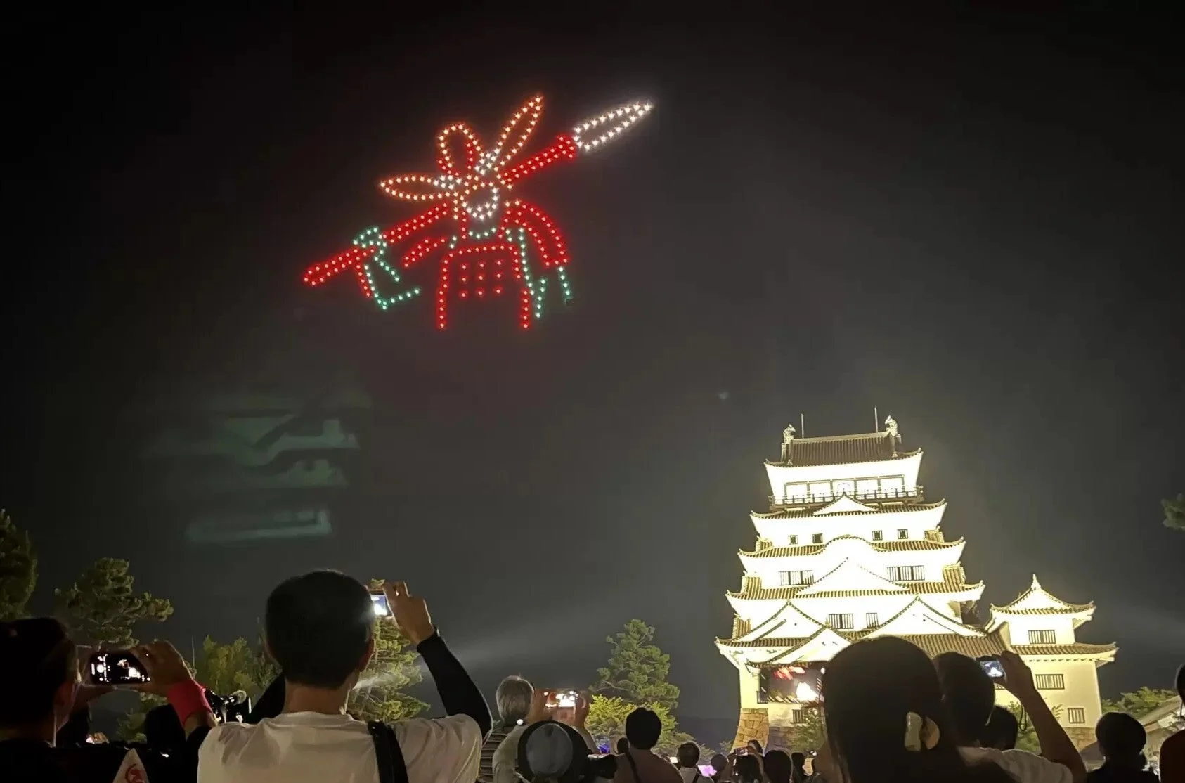 夜空に武士の光が描かれたドローンショーと福山城