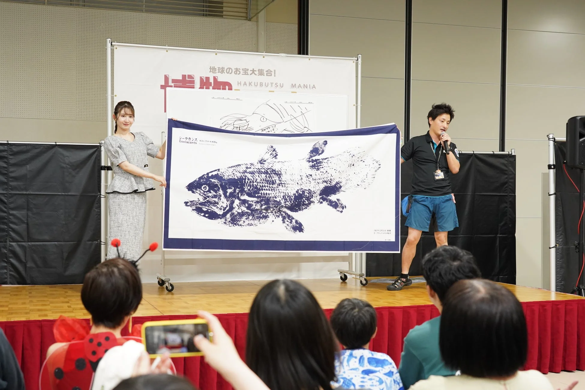 シーラカンスのイラストを囲むステージ登壇者