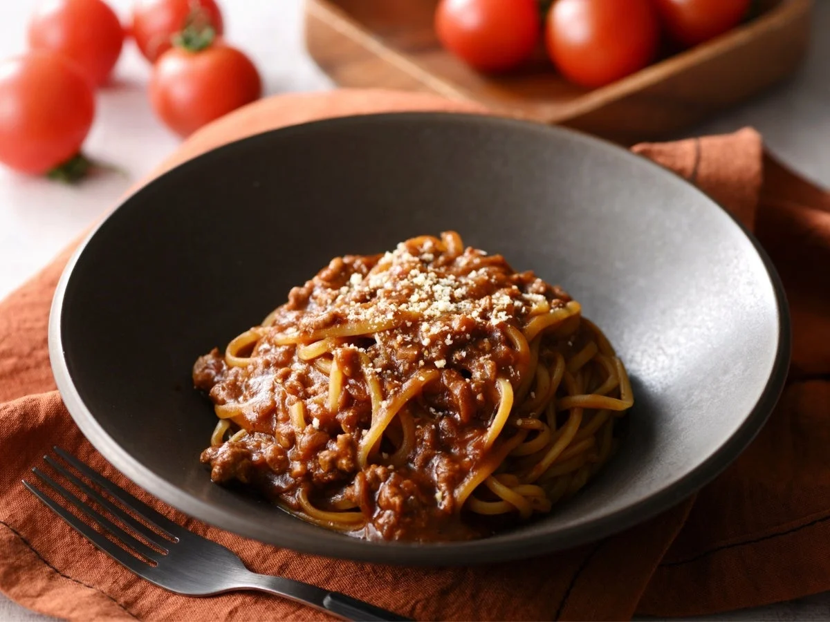 暗い色の器に盛られたボロネーゼスパゲッティ