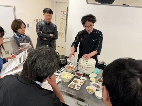 シェフが参加者に料理を実演指導している様子