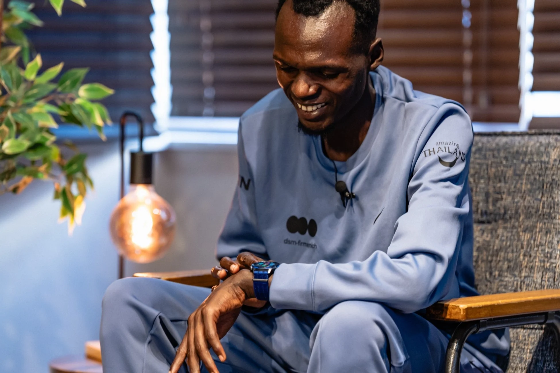 青いトラックスーツを着た男性が、笑顔で腕時計を見ている