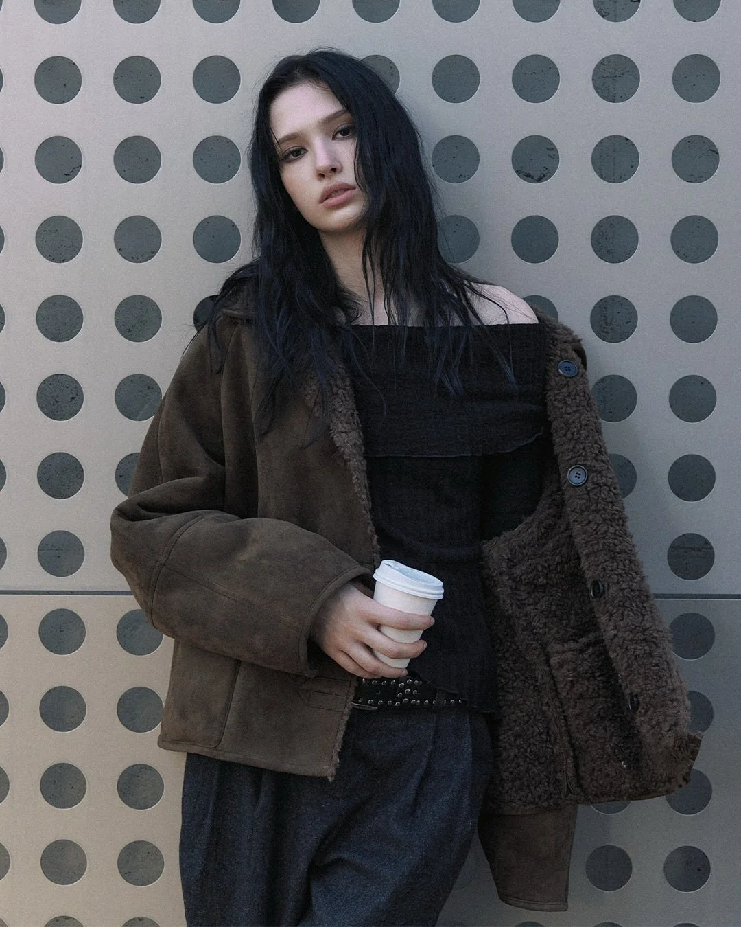 女性がムートンジャケットを着てコーヒーカップを持っている画像